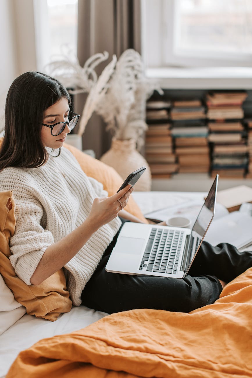 young lady using laptop and smartphone to engage with her instagram audience