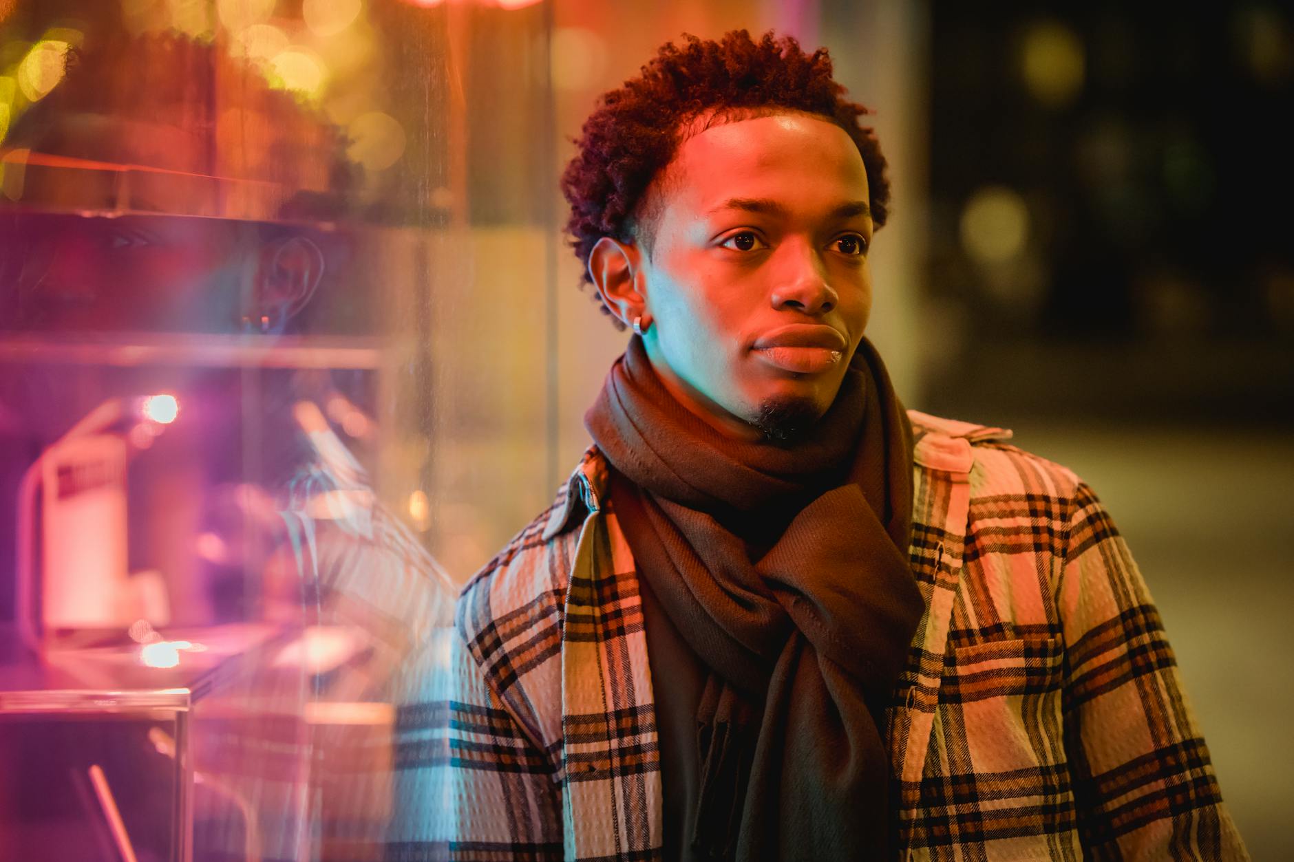 thoughtful black man near window of building