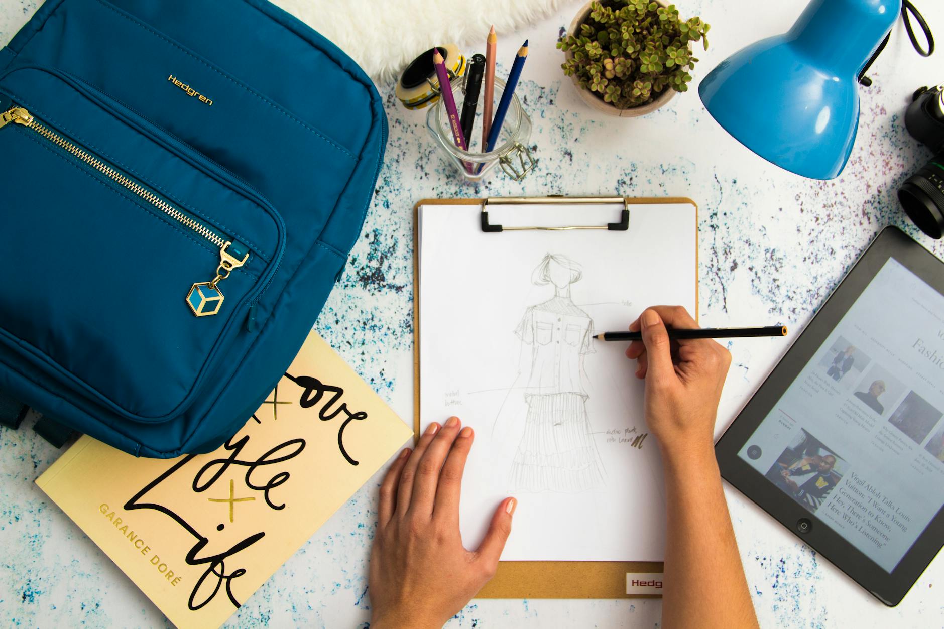 designer sketching fashion design on printer paper with clip board